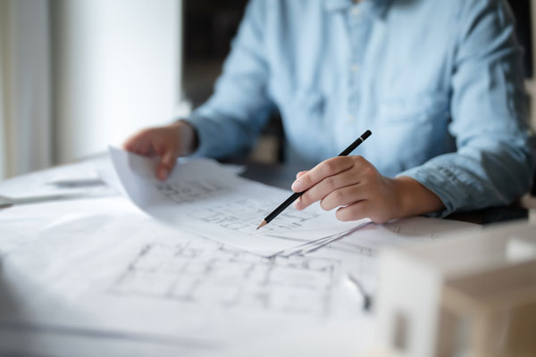 Man looking at design plans, holding pencil in hand